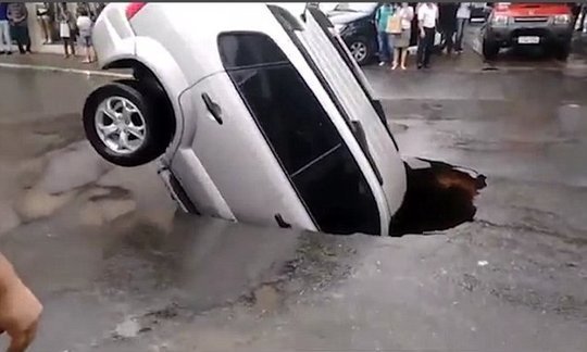 Car teeters on the edge of abyss after it falls into a sinkhole
